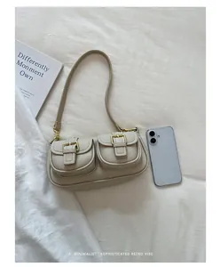Bovenaanzicht van crème vintage baguette tas met gouden gespen naast telefoon voor schaal
