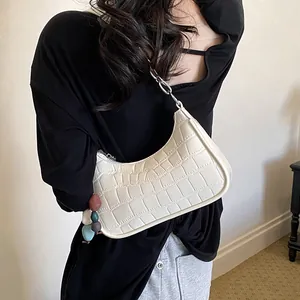 Detailed view of the off-white crocodile pattern crescent hobo bag with beaded accessory