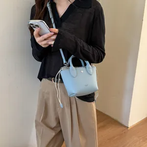 Détail du mini sac seau bleu clair avec cordon de serrage et logo FAN'TOB LONDON.