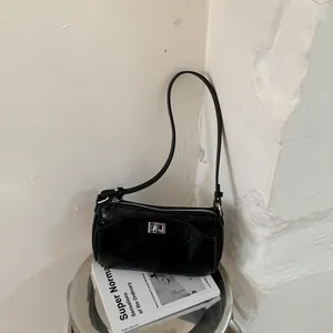 Vue détaillée d'un sac à bandoulière minimaliste en cuir noir froissé avec fermoir