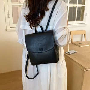 Rear view of a woman wearing a stylish black leather backpack with a white trench coat.
