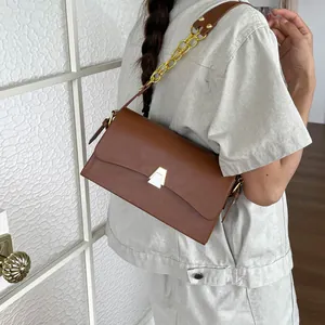 Detail view of stylish brown leather shoulder bag featuring an elegant gold chain strap