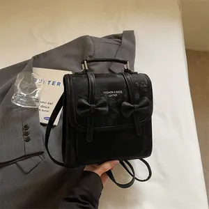 Dettaglio dello zaino nero in stile college con fiocchi decorativi e manico superiore.