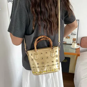Detailed shot of a gold metallic bucket bag with bamboo handles and floral embroidery.