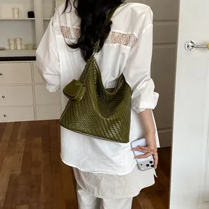 Stylish olive green woven shoulder bag on model featuring a matching mini pouch charm