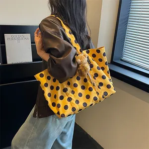 Stylish large yellow polka dot tote bag for women with a cute brown bear bag charm detail
