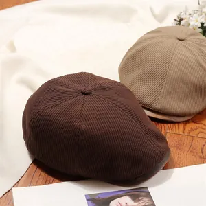 Vintage knitted newsboy caps in brown and khaki textures, detailed view on wooden floor
