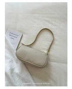 Beige baguette-tas van generfd leer op een minimalistische witte stoffen achtergrond