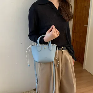 Détail du mini sac seau bleu clair avec doublure à cordon et bandoulière amovible
