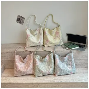 Detailed view of floral embroidered shoulder bags in multiple soft pastel colors