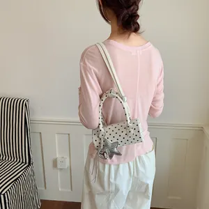 Back view of a polka dot cylinder handbag with star charm in a lifestyle setting