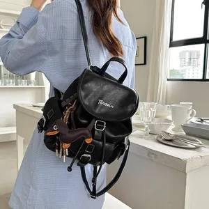 Chic black faux leather backpack with white stitching and dog charm on a model