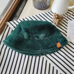 Detailed view of a dark green faux fur bucket hat for winter on a striped surface