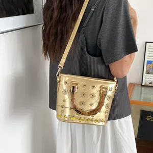 Metallic gold bucket bag with star studs and bamboo handles worn crossbody style