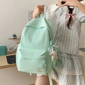 Detailweergave van een mintgroene rugzak voor scholieren met sterborduurwerk en pluche hanger