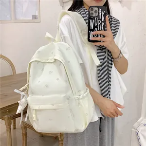 Close-up detail of white floral backpack featuring stylish ribbon and star pendant