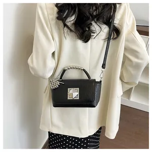 Detailed view of a fashionable black small square bag with silver beaded handle.
