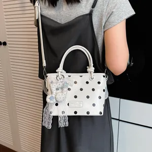 Trendy white handbag with black polka dots featuring a cute lace musical note charm