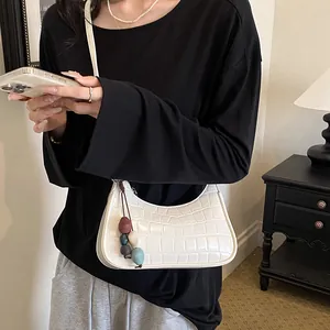 Detailed side view of white crocodile pattern hobo bag with a colorful bead charm