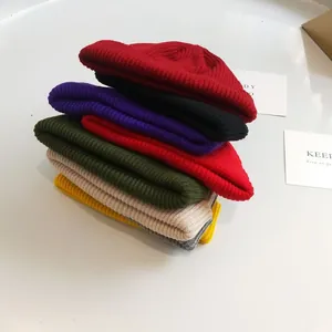Close-up stack of colorful short knitted beanie hats in various vibrant fashion shades