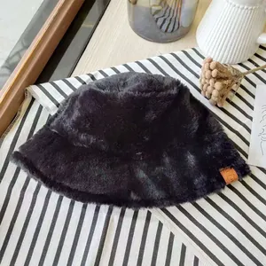 Close-up of black faux fur bucket hat with soft plush texture on striped background