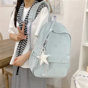 Stylish mint green floral student backpack worn by model in a casual indoor setting
