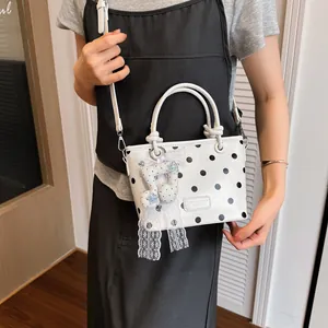 Stylish white polka dot handbag with elegant star charm accessory worn by fashion model
