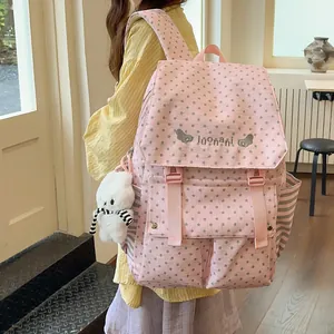 Detailed view of fashionable pink star pattern backpack with cute white plush bear charm.