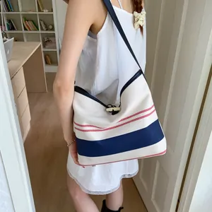 Side view of woman carrying a striped canvas tote bag with wooden toggle closure