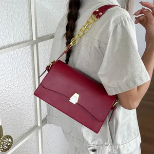 Close-up view of a chic red shoulder bag featuring a gold chain strap and geometric clasp