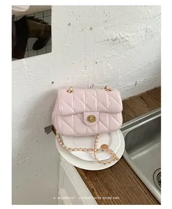 Detailopname van roze gewatteerde tas met gouden ketting en luxe gouden draaisluiting