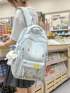 Zaino scolastico azurro con ricami floreali per ragazze adolescenti in un supermercato