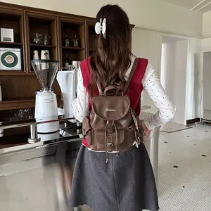 Lifestyle view of a brown vintage faux leather backpack on a model in a cafe setting.