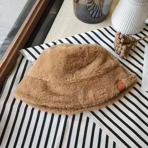 Detailed close-up of a brown plush faux fur winter bucket hat on striped fabric