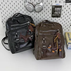 Vintage faux leather backpacks in black and brown, featuring decorative dog charms.