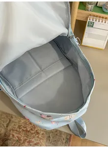 Macro view showing the spacious interior pockets of a light blue student backpack