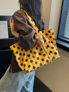 Large yellow polka dot tote bag with cute teddy bear charm for women's daily commute.