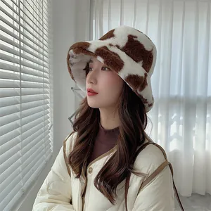 Close-up detail of a soft plush cow pattern bucket hat worn by a model in winter