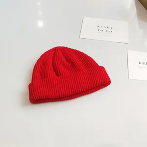 Detailed close-up of the red knitted texture on a minimalist melon cap style beanie hat.