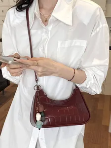 Elegant dark red crocodile pattern crescent crossbody bag with decorative bead charm