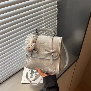 Primo piano di zaino grigio strutturato con ciondolo a coniglio e fiocco