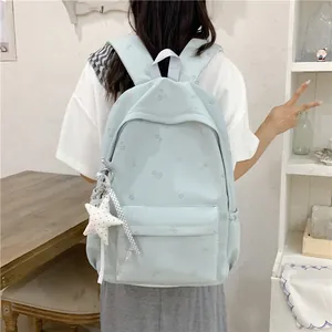 Detail view of a light blue student backpack with floral patterns and a star charm