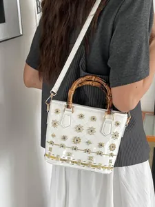 Elegant white quilted handbag featuring a natural bamboo handle and golden floral studs
