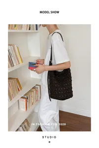 Detailansicht einer modischen braunen geflochtenen Eimertasche, von einem Model getragen.
