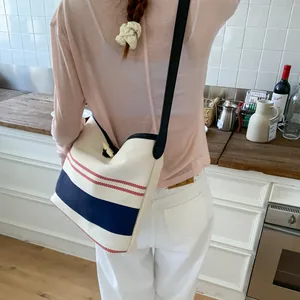 Detail view of a striped canvas tote bag worn over the shoulder in a lifestyle setting.