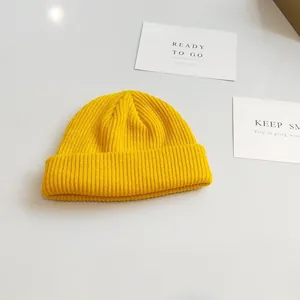 Detail view of a bright yellow ribbed knit beanie with a minimalist folded cuff design.