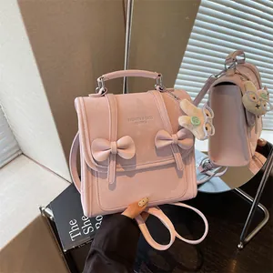 Dettaglio ravvicinato di uno zaino rosa in stile preppy con fiocchi e un ciondolo a coniglietto