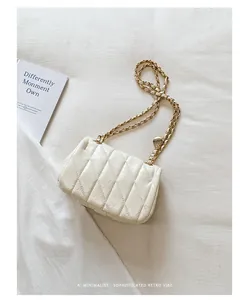 Detail van een witte gewatteerde kettingtas met gouden hardware en mooie retro stijl.