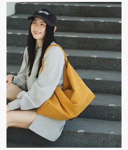 Detailed lifestyle shot of a model carrying a large yellow suede tote bag on stone stairs