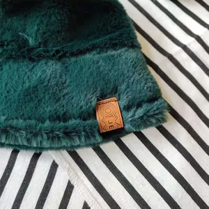 Close-up detail of dark green faux fur bucket hat with leather brand tag